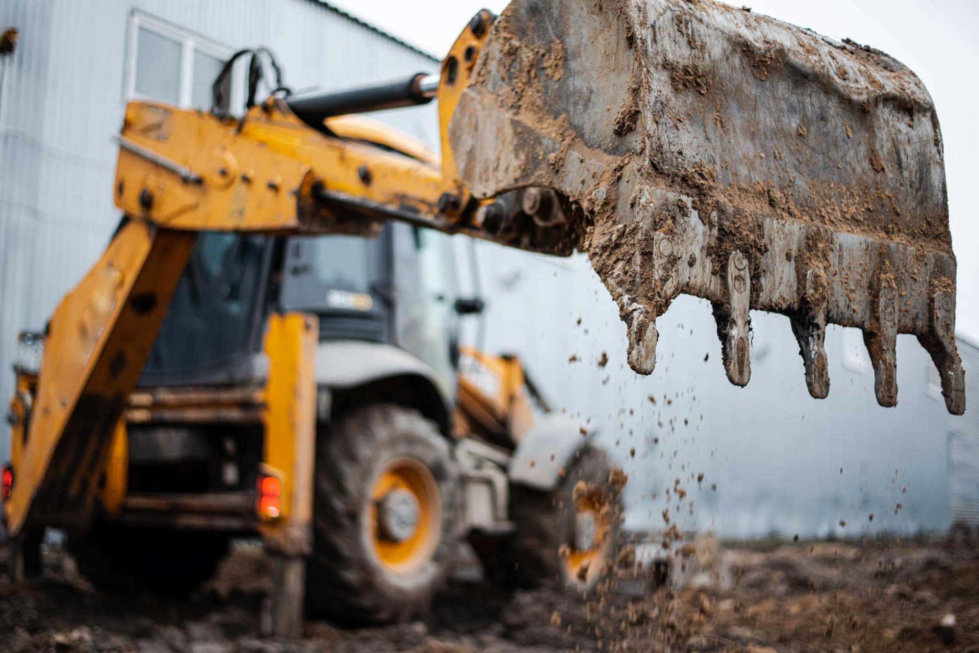Excavator bucket lifting spoil on an enabling works site