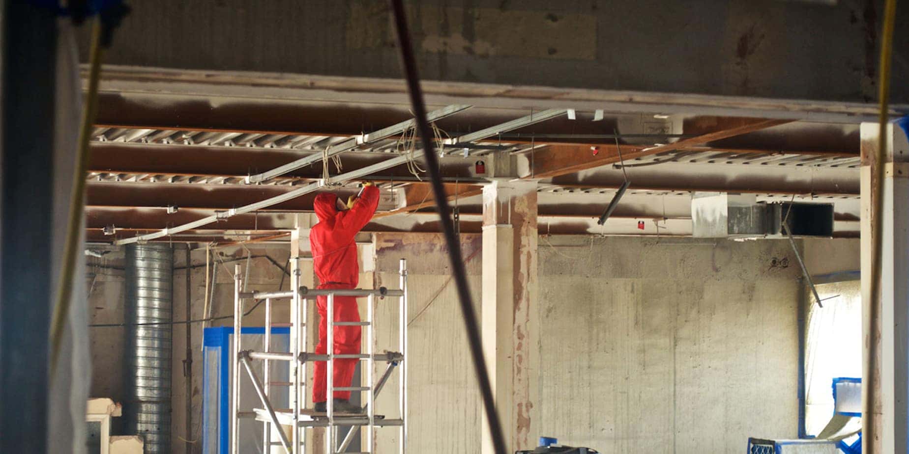 Spectra operative in protective coveralls working at height on a stripped commercial floorplate